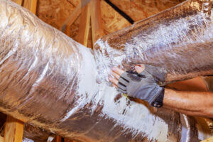 Hands of a person installing air duct pipeline for HVAC system during a new construction