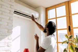 Improving ventilation in your home - A man adjusting the temperature of an AC unit.