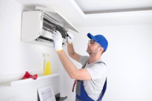 AC tune up near me: Service guy cleaning and maintaining an air conditioning unit