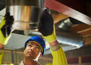 Repair duct leaks with Aeroseal - HVAC tech inspects air duct for Aeroseal prep.