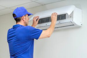 a man in a blue cap fixing a air conditioner
